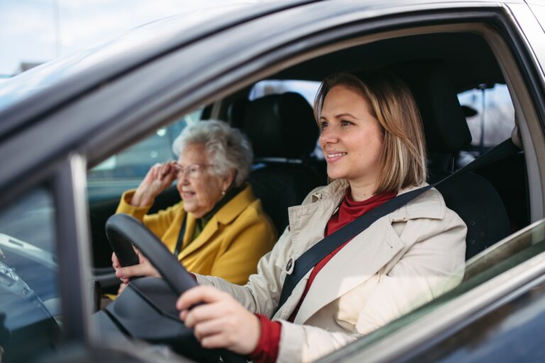 Granddaughter driving her elderly grandmother in the car, taking her to the doctor, shopping or to