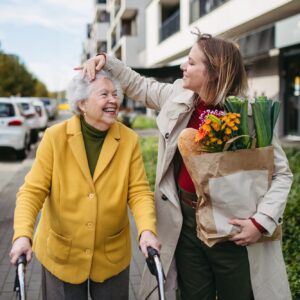 Mature granddaughter carrying grandmother's shopping bag. Senior woman and caregiver going to home