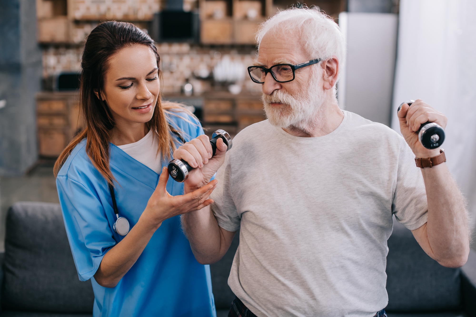 Nurse assisting senior man exercising with dumbbells